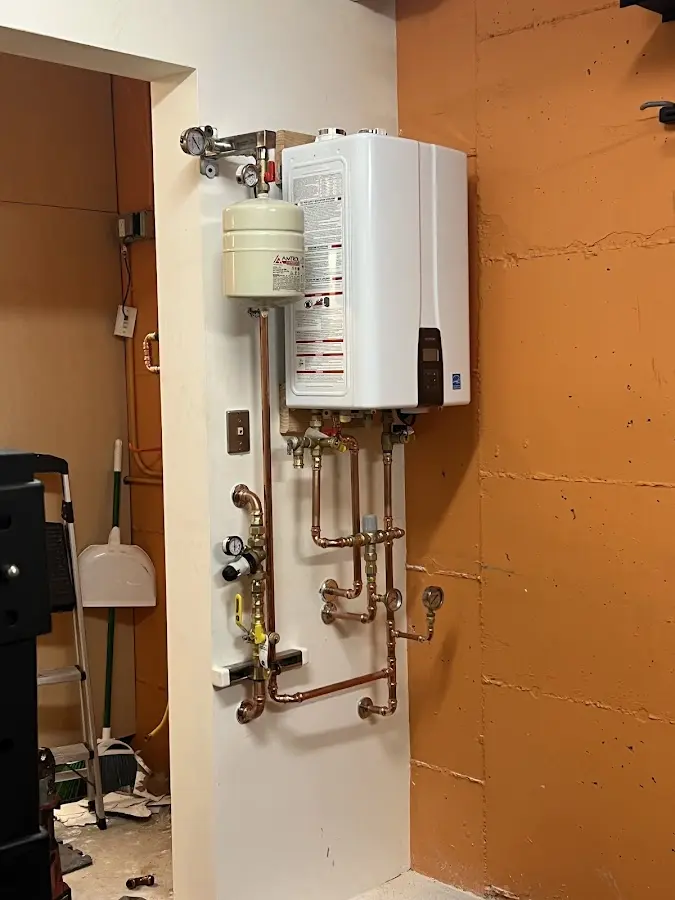 Plumbing technician inspecting water heater connections in East Hempfield